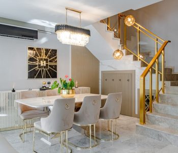 Modern dining room with marble table, gold accents, and stylish lighting.