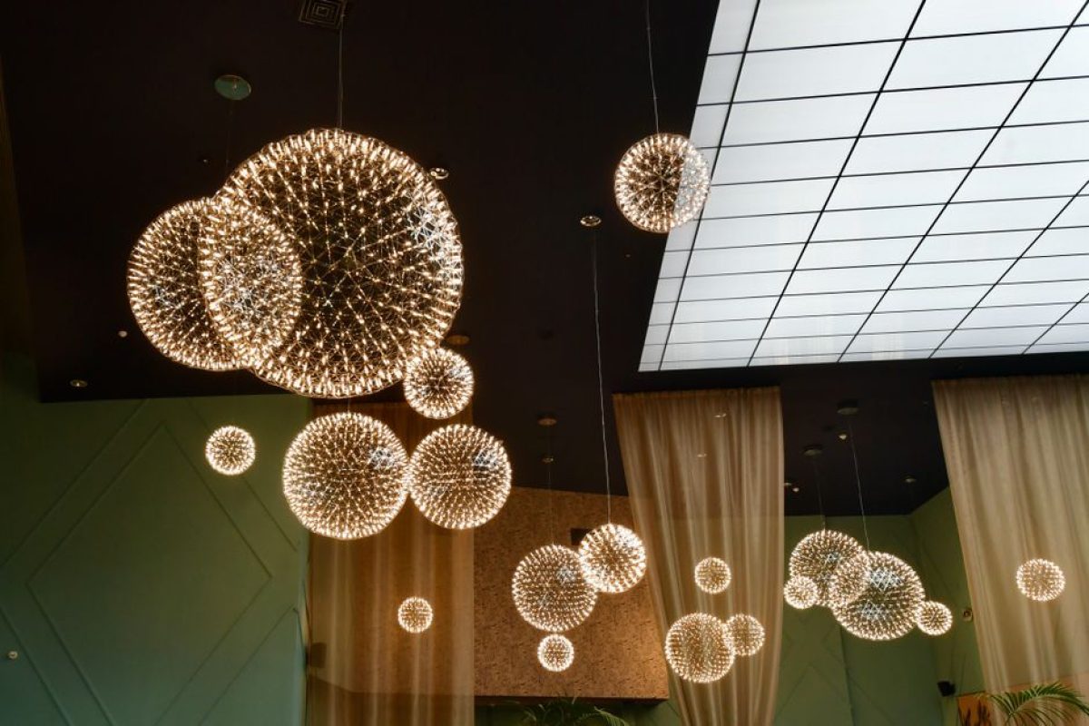 Elegant modern interior with glowing spherical chandeliers and glass ceiling.