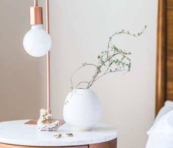 Stylish bedroom with a minimalist lamp and vase on a marble side table.